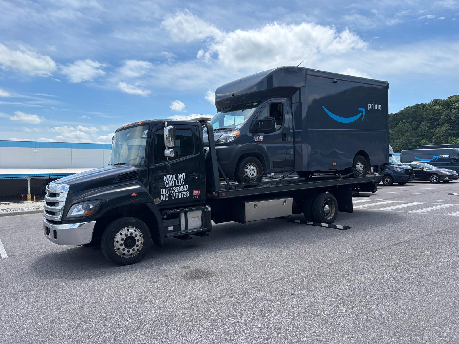 Move Any Car LLC towing a delivery van on a flatbed truck