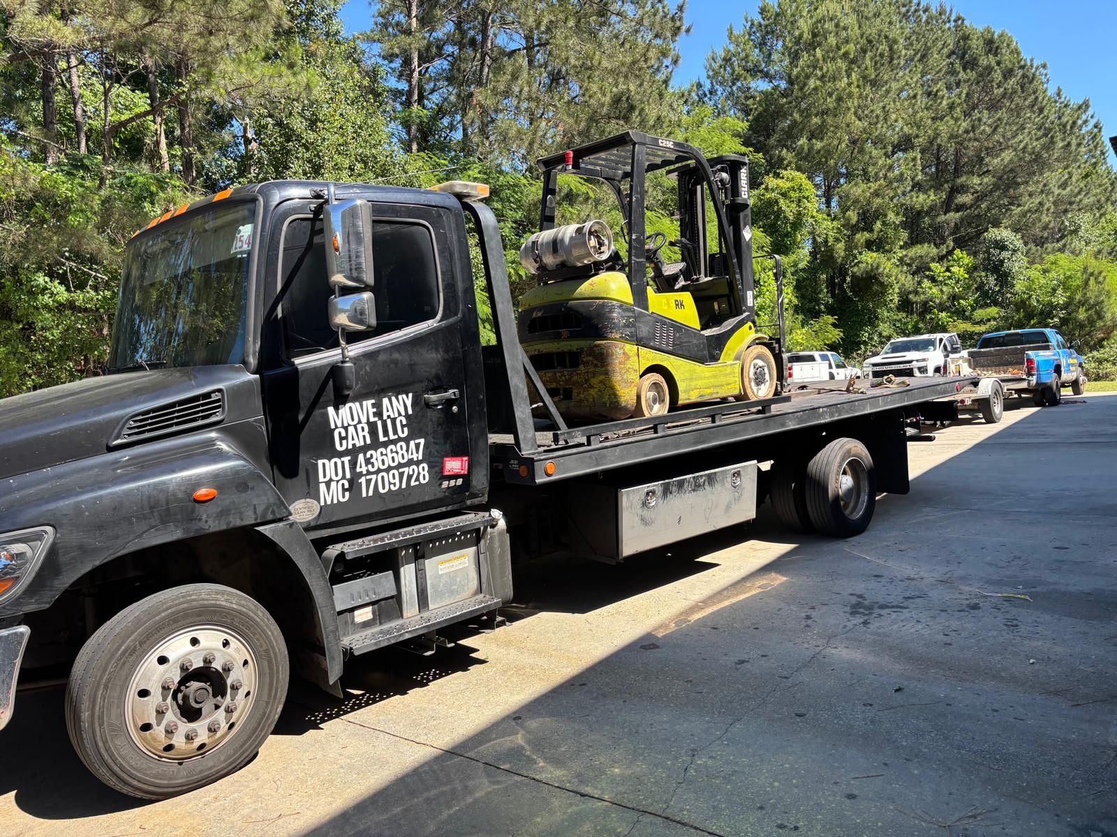 Move Any Car LLC hauling a forklift on a flatbed truck